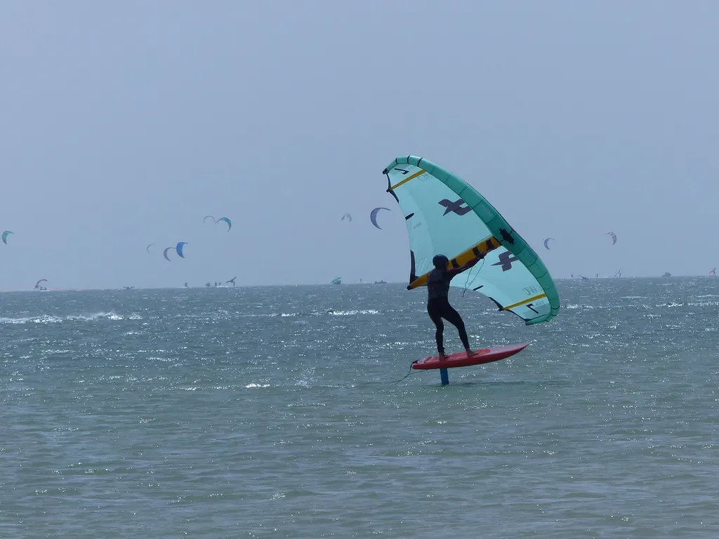 Une aile turquoise et une planche rouge sur la lagune