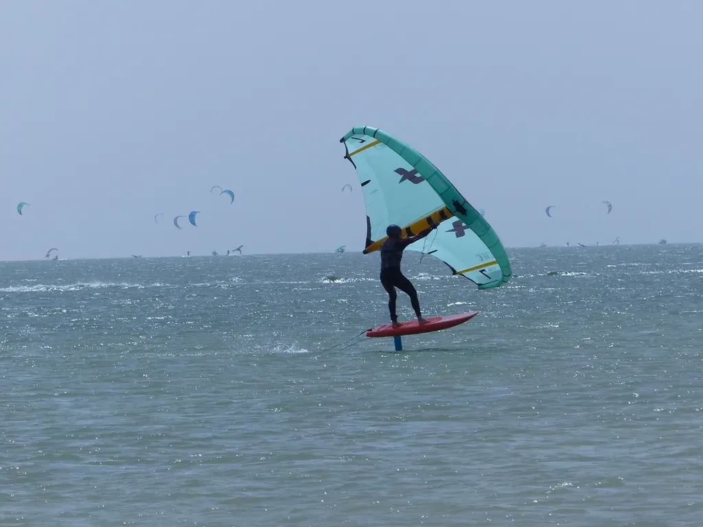 Une aile turquoise et une planche rouge sur la lagune